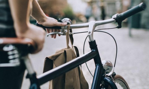 a person holding a bag on a bicycle