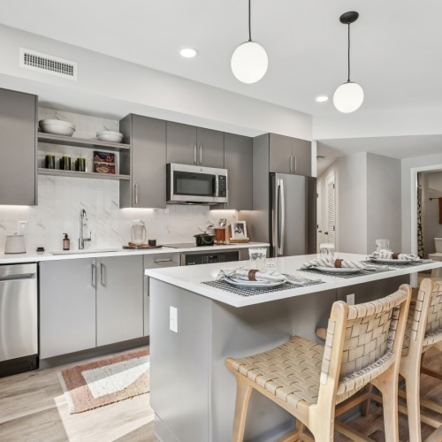 Designer Kitchens kitchen with island, barstools, white countertops and backsplash